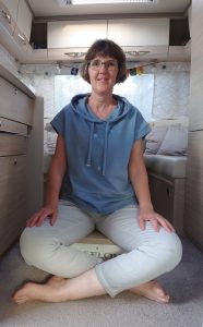 Bettina Viergutz sitzt im Wohnmobil auf dem Reise-Osflow um Rückenschmerzen im unteren Rücken zu lindern.