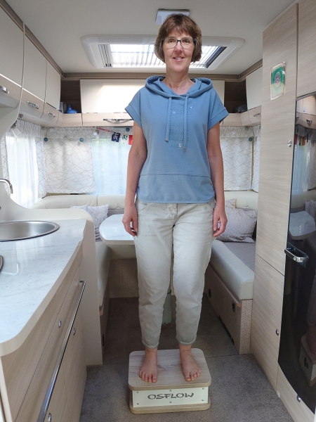 Bettina Viergutz steht im Wohnmobil auf dem Reise-Osflow um den Körper zu entspannen und gleichzeitig auszurichten.