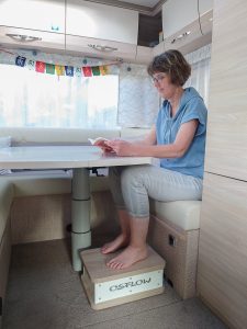 Bettina Viergutz sitzt im Wohnmobil und hat ihre Füße auf dem Reise-Osflow um Stress abzubauen.